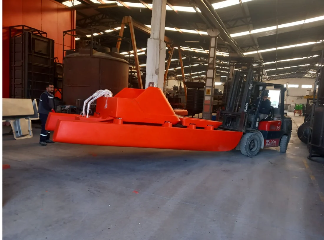 Atölyede forkliftle taşınan turuncu renkli büyük hacimli plastik gövde